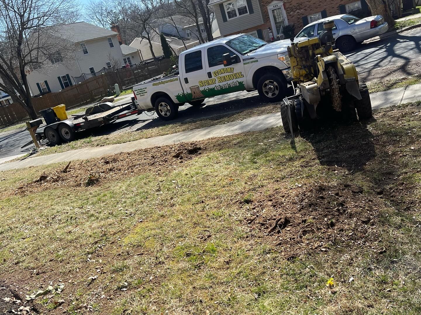 A truck is parked on the side of the road next to a stump grinder.