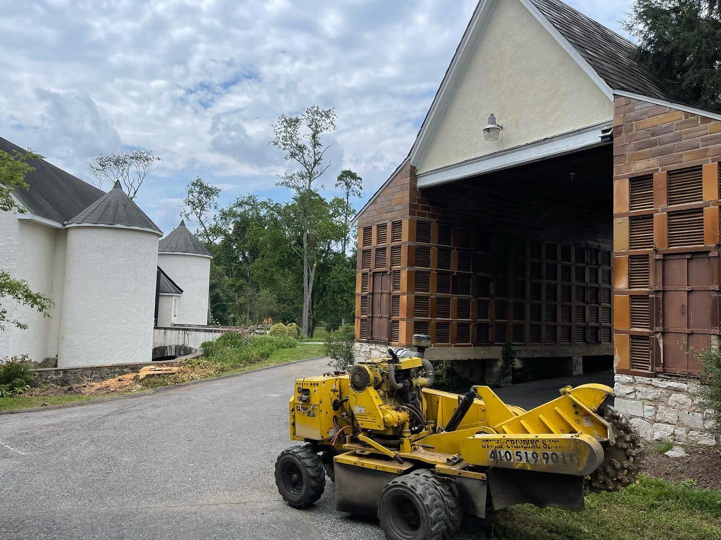 A yellow stump grinder is parked in front of a building.