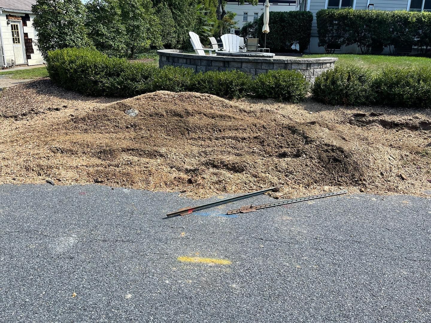 A pile of dirt is sitting on the side of a road next to a house.