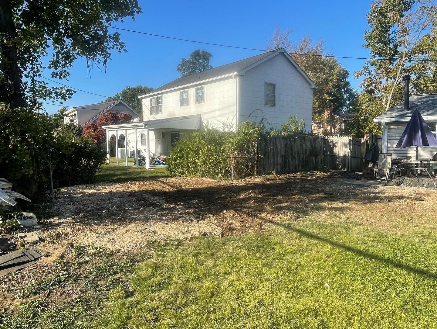 A white house is sitting in the middle of a lush green yard.