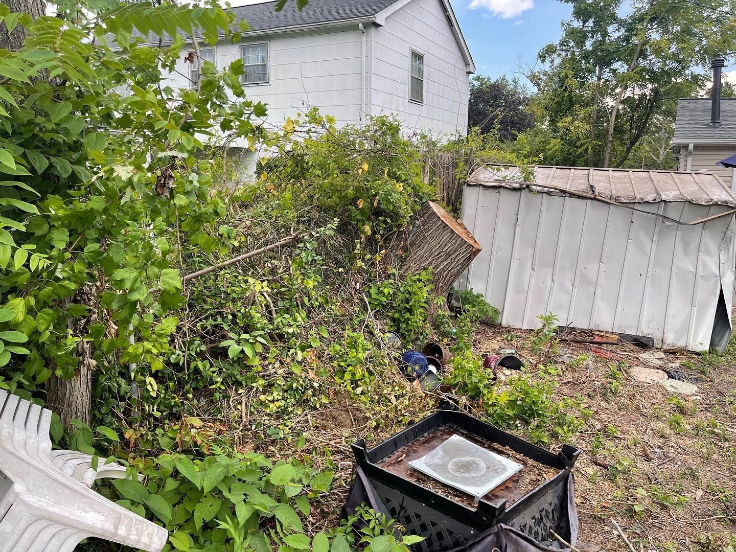A backyard with a fire pit and a white house in the background.