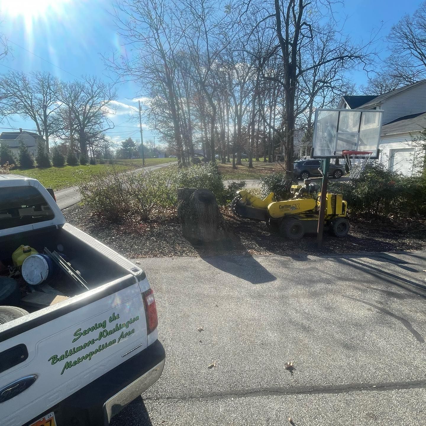 A white truck is parked in a driveway next to a yellow lawn mower.