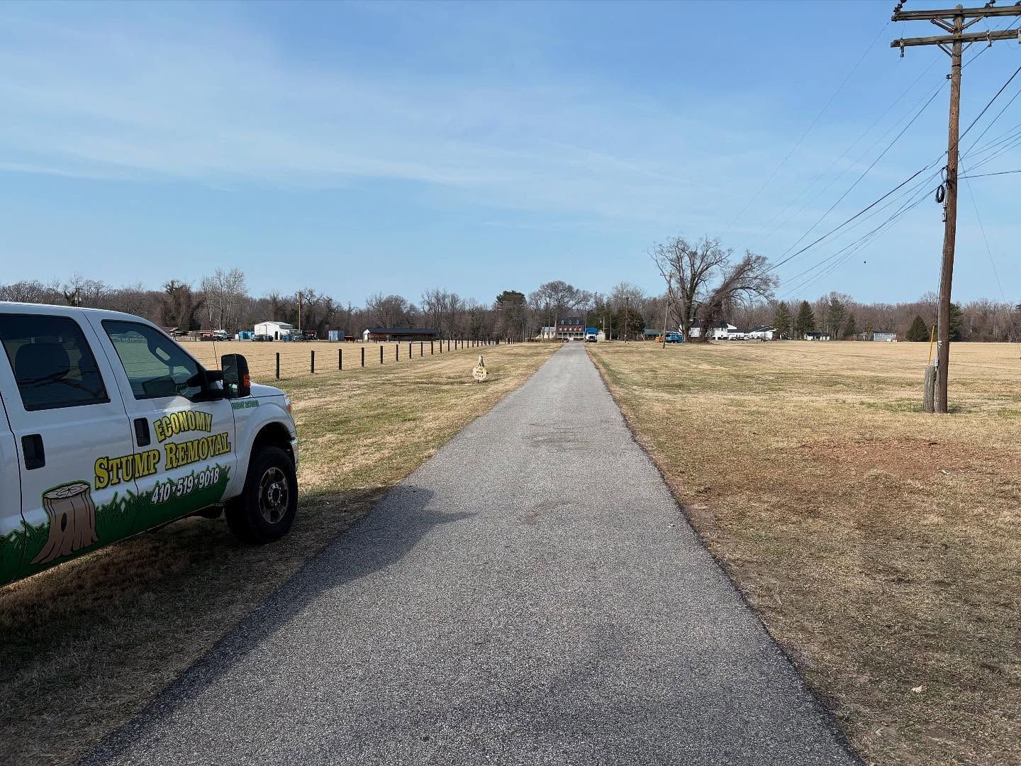 A truck is parked on the side of a road next to a field.