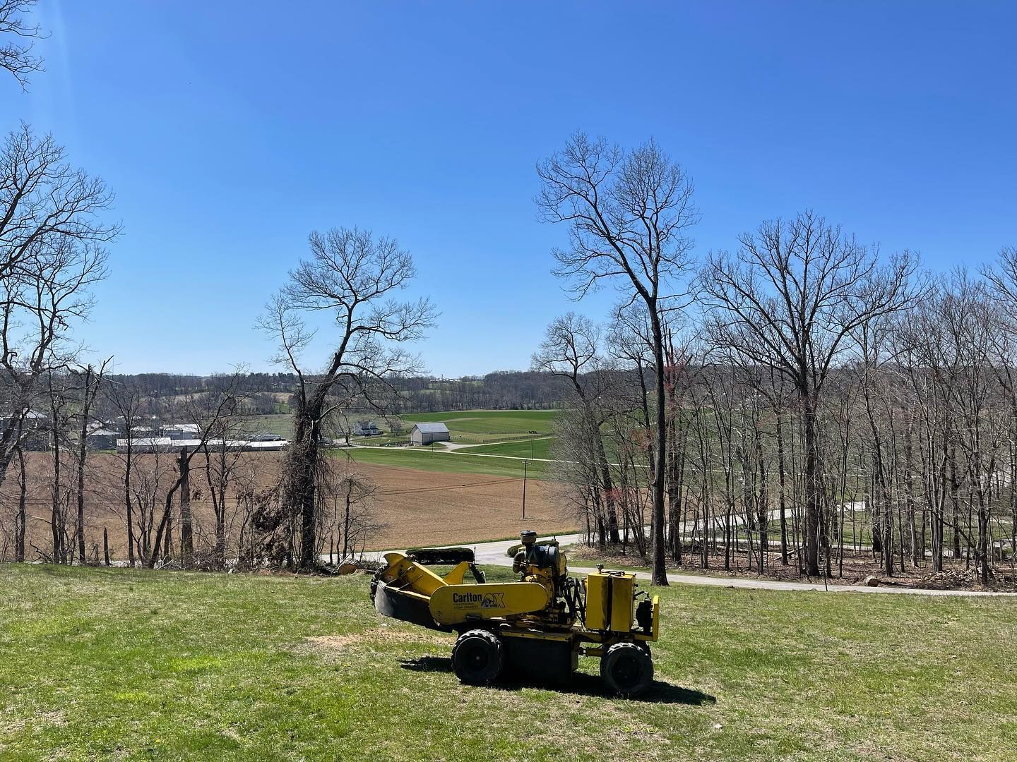 A yellow tractor is sitting on top of a lush green field.