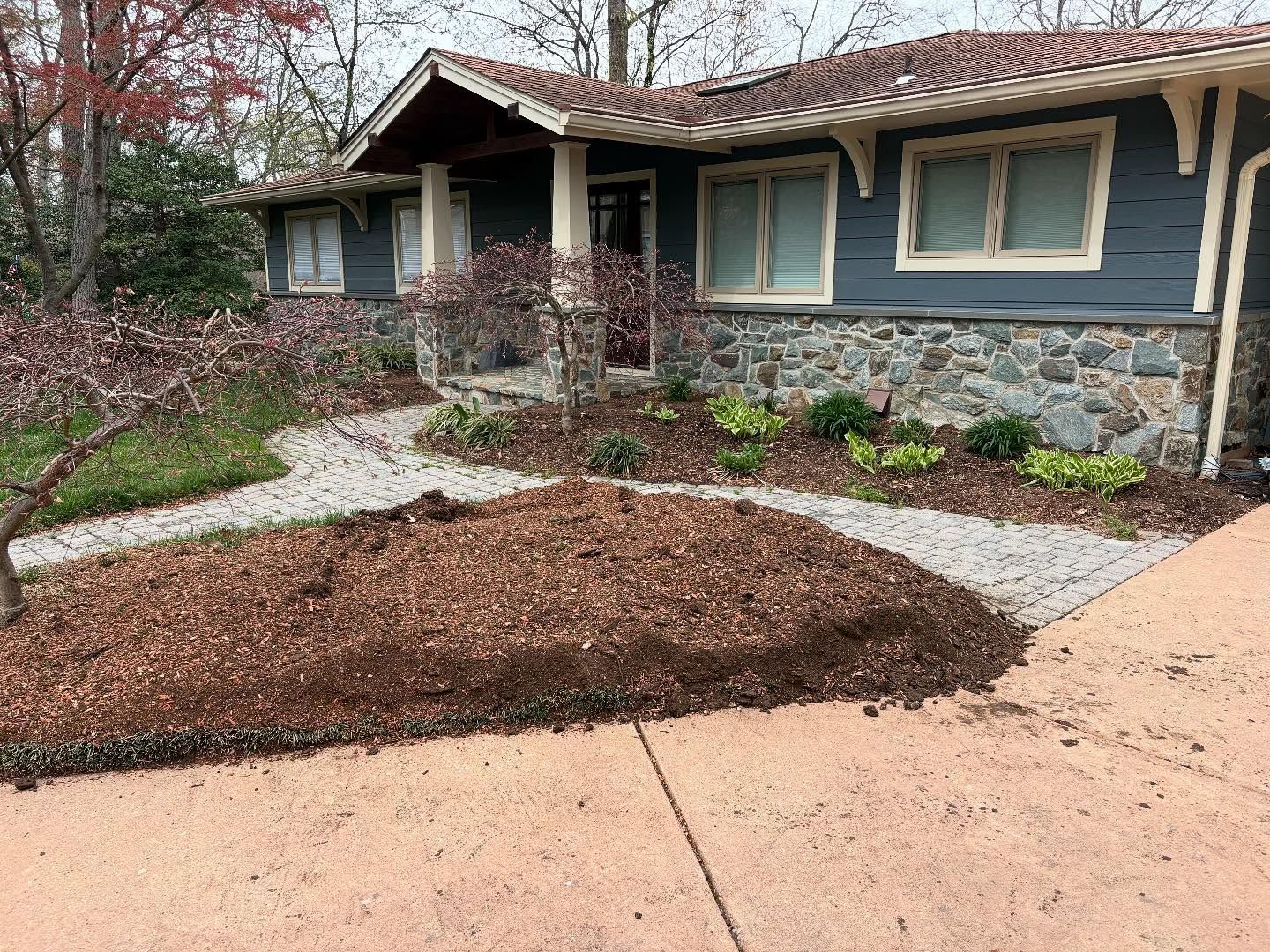 A blue house with a stone facade and a walkway leading to it.