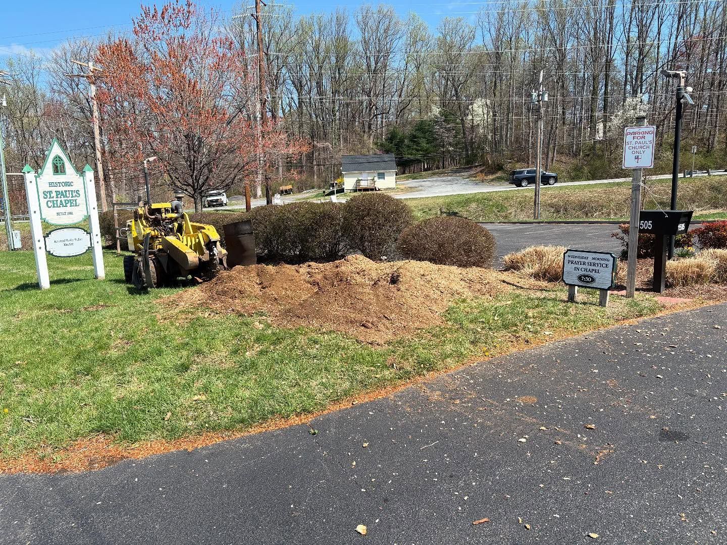 A stump grinder is being used to remove a tree in a parking lot.