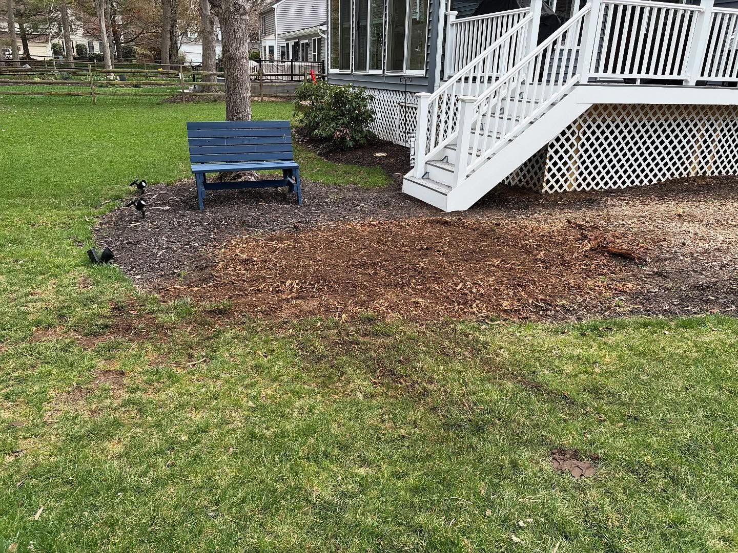 A blue bench is sitting in front of a house with stairs.