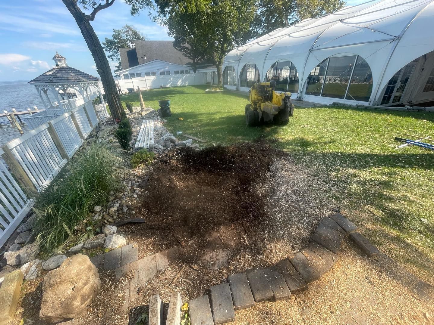 A stump grinder is cutting a tree stump in a yard.