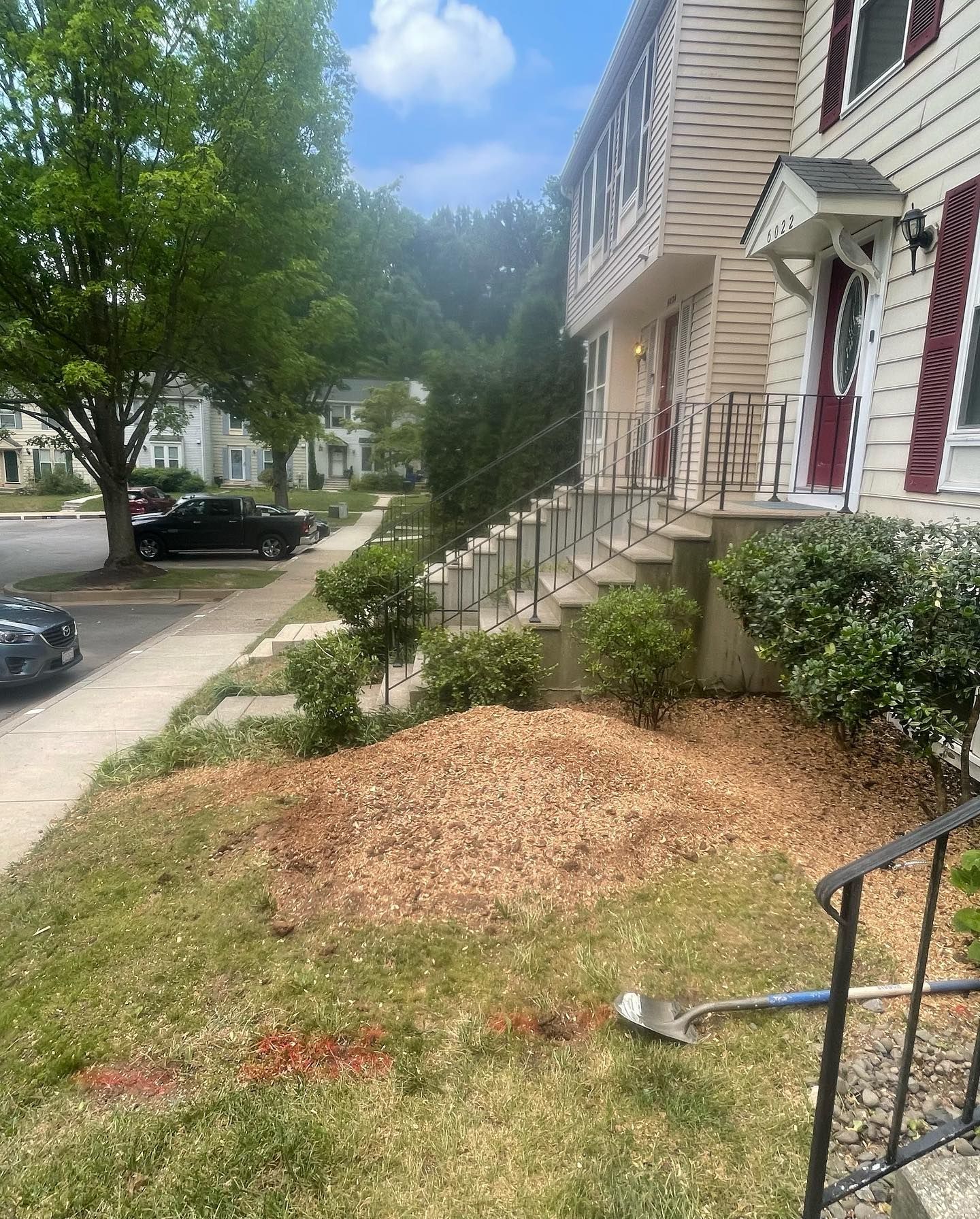 A shovel is sitting in the grass in front of a house.