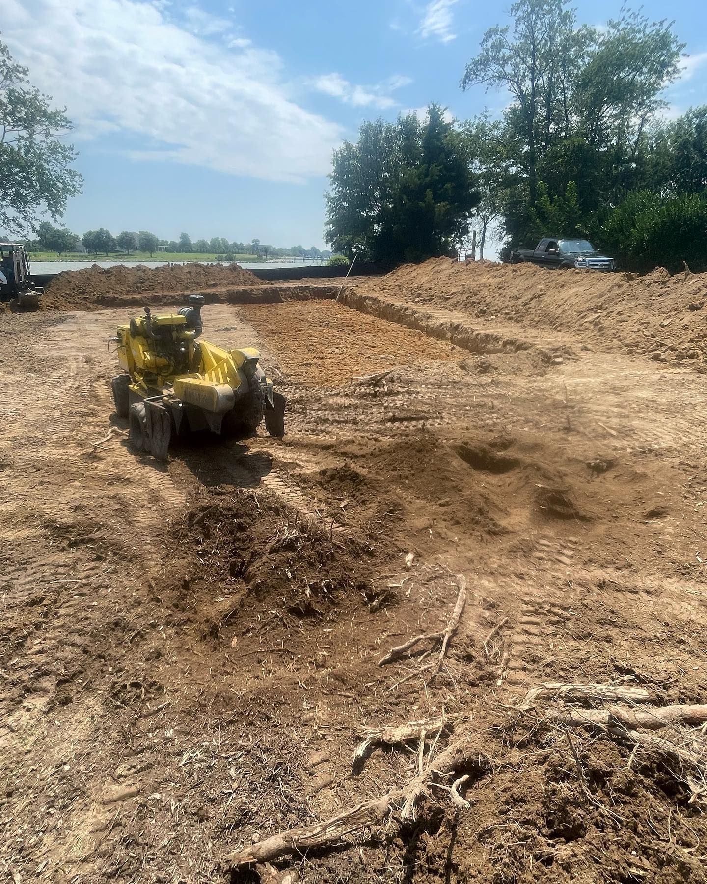 A yellow tractor is driving through a dirt field.