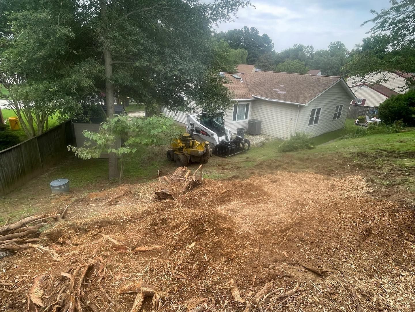 A large pile of wood chips is sitting in front of a house.