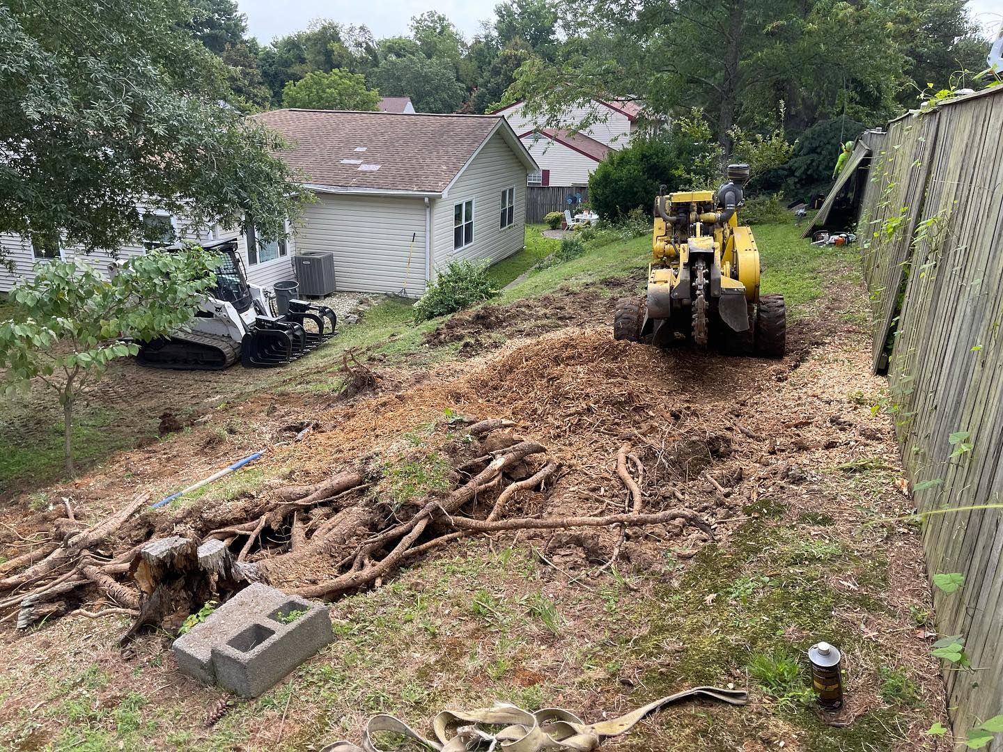 A stump grinder is being used to remove a tree stump in a backyard.