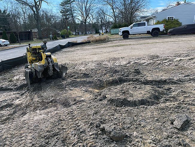A white truck is parked in a dirt lot next to a bulldozer.