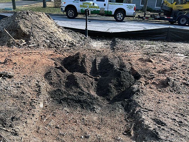 A white truck is parked next to a pile of dirt.