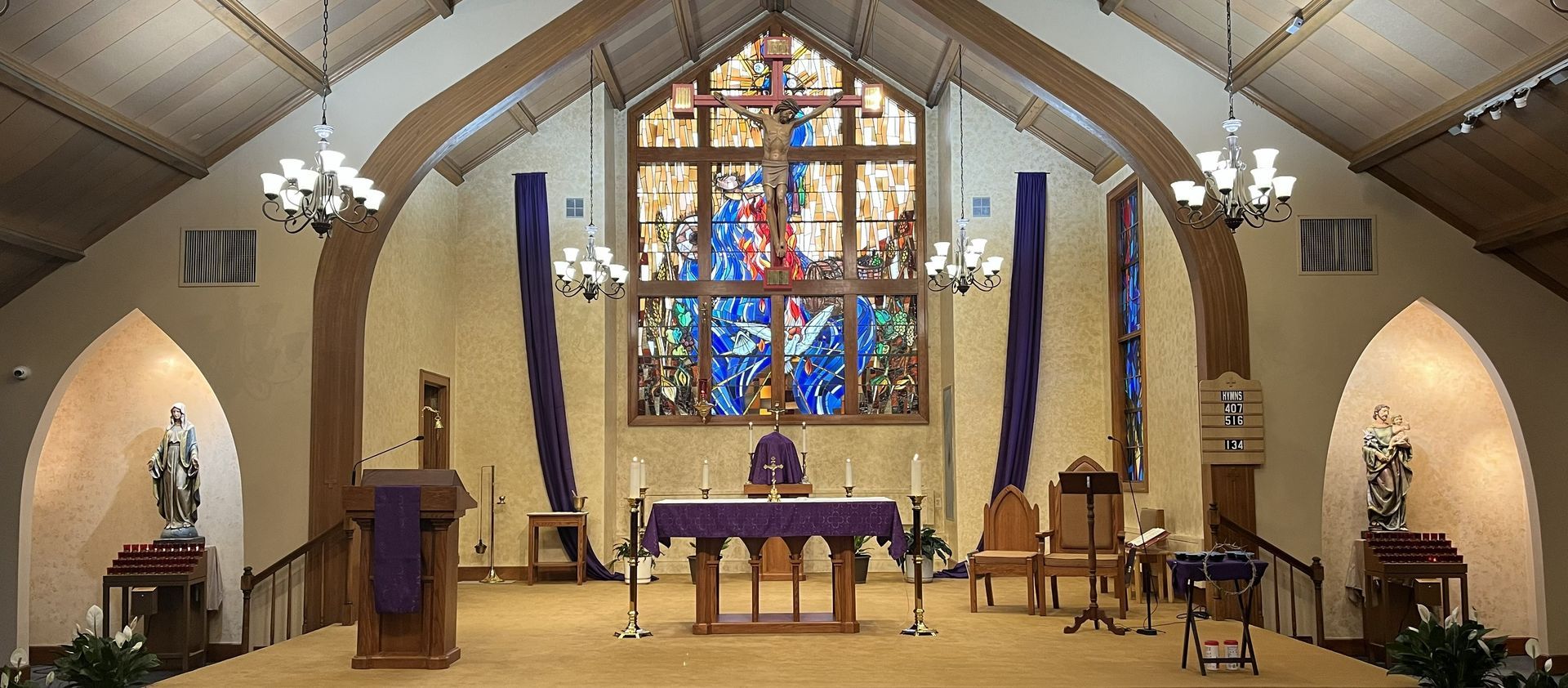 Church sanctuary with altar, stained glass, blue banners, and a central cross behind the lectern
