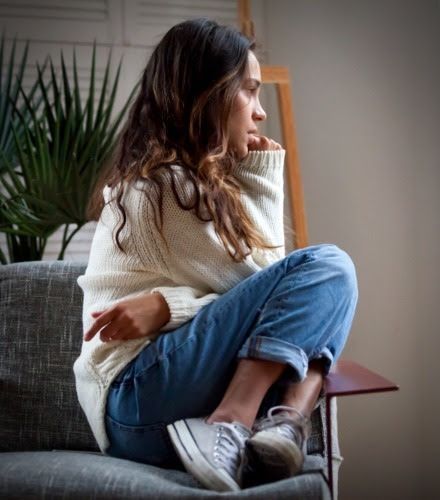 A woman is sitting on a couch with her legs crossed