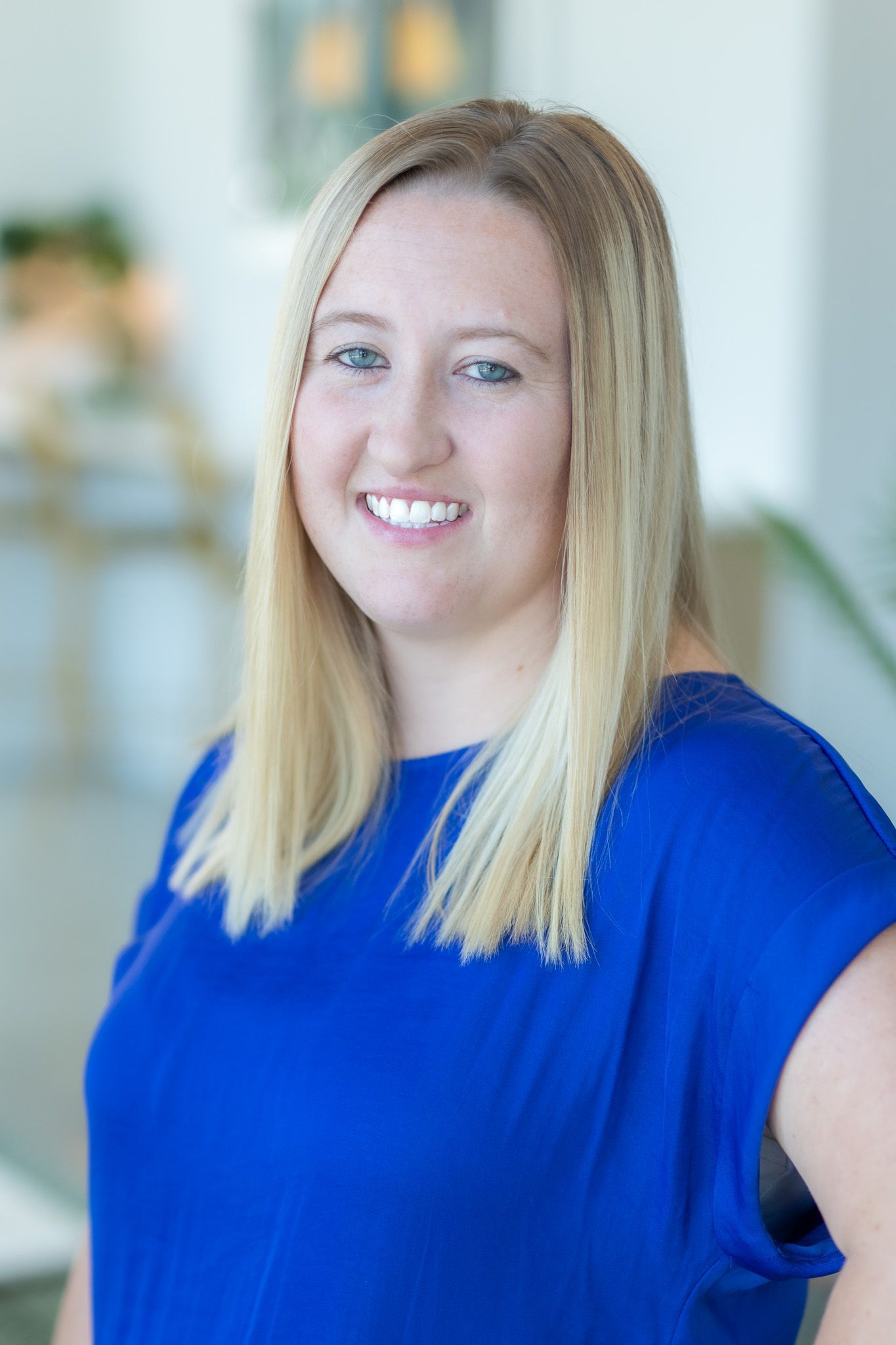 The woman is wearing a blue shirt and smiling for the camera.