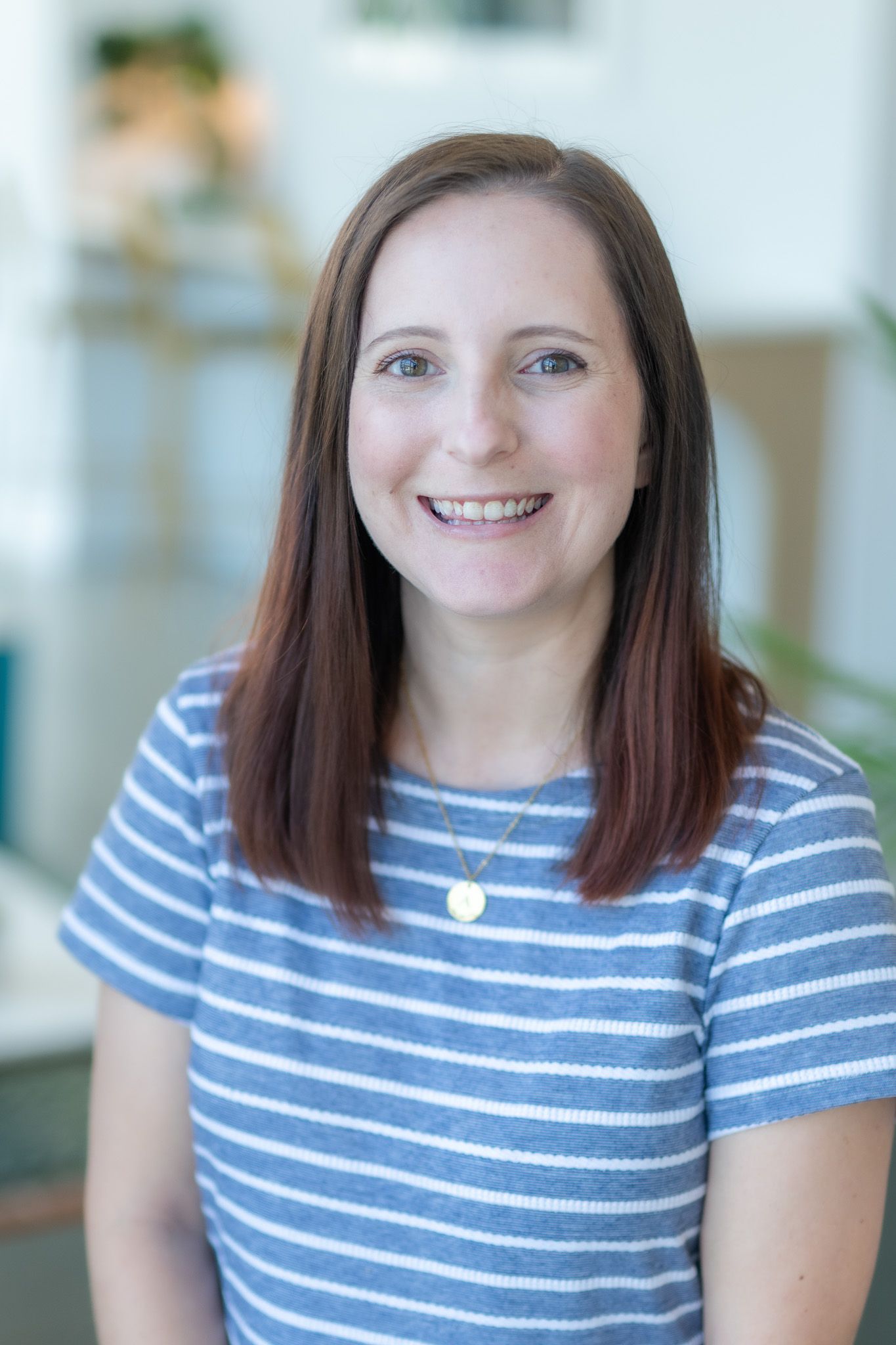 A woman in a blue and white striped shirt is smiling for the camera.