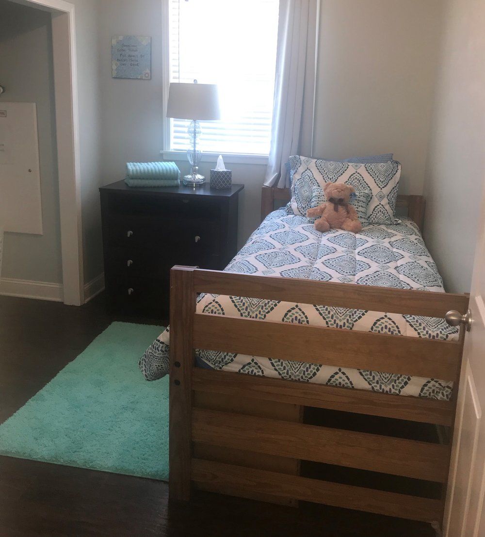 A bedroom with a single bed and a teddy bear on the bed.