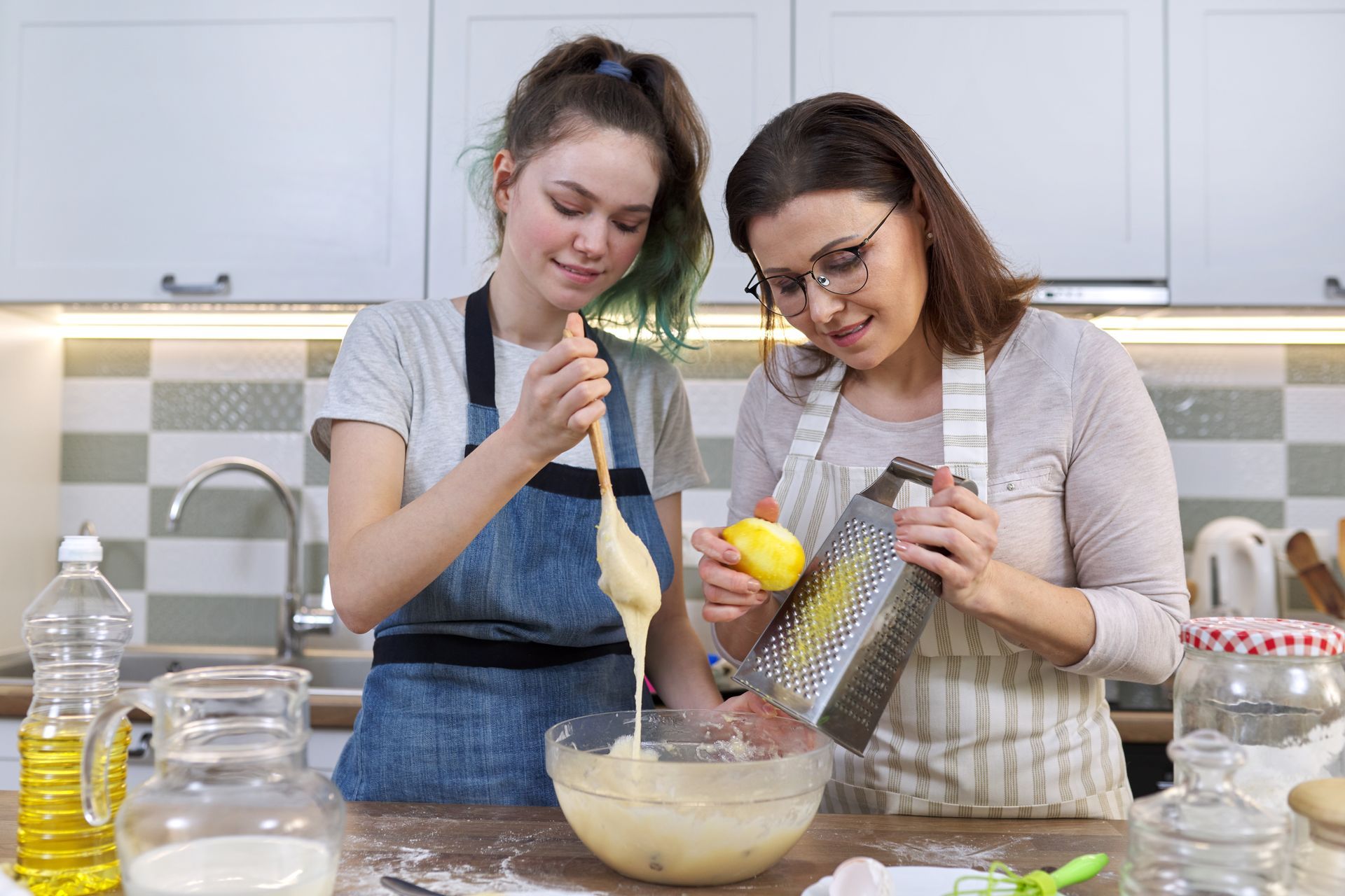 A mother and daughter are preparing food in a kitchen.