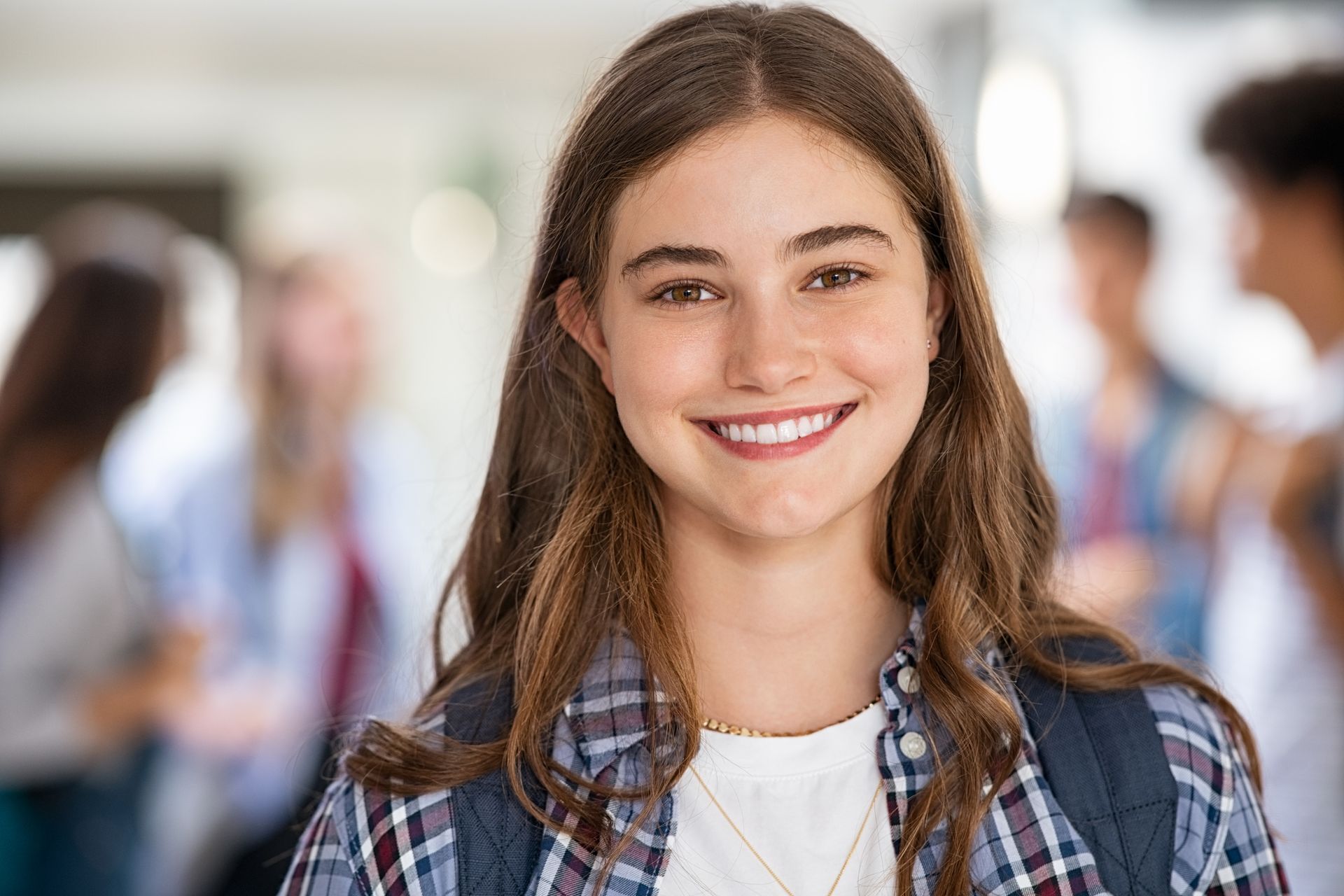 A young girl with a backpack is smiling for the camera.