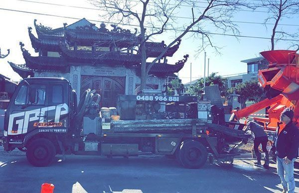 Concrete truck pouring concrete on a construction site. The truck is dark blue.