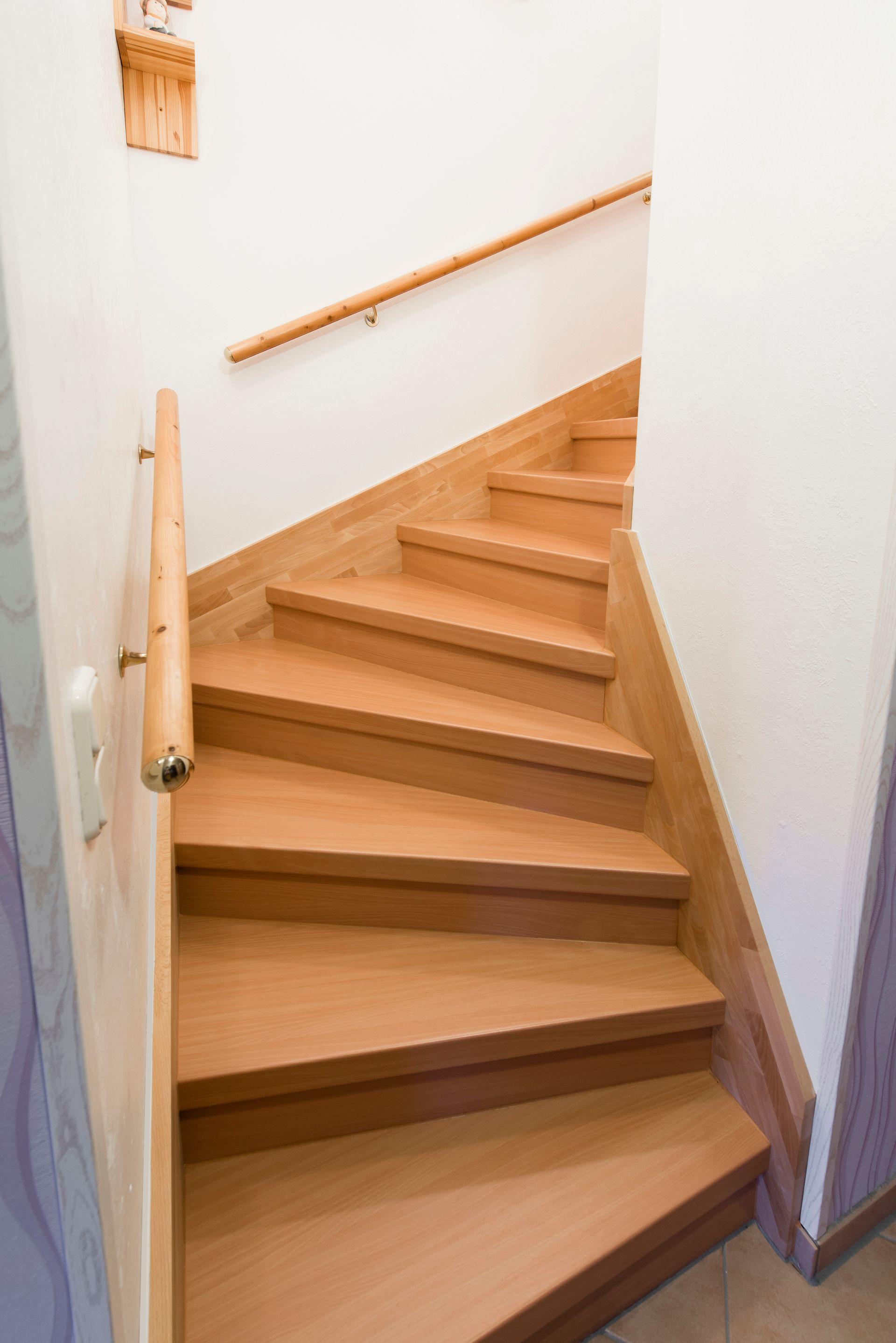 eine Holztreppe mit einem Holzhandlauf und einer weißen Wand.