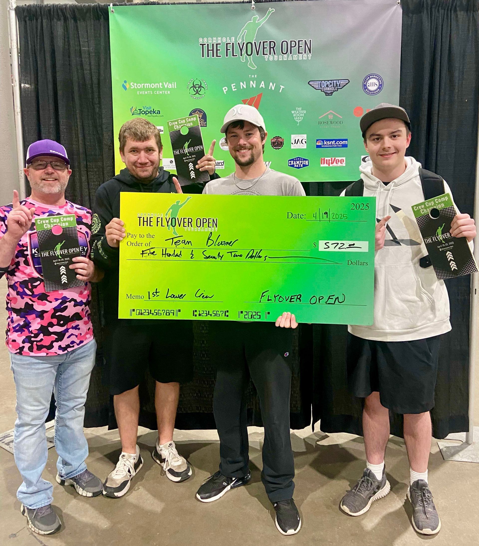 A group of young men are standing next to each other holding a large check.