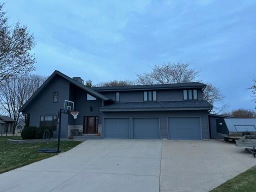 A large gray house with a basketball hoop in front of it.