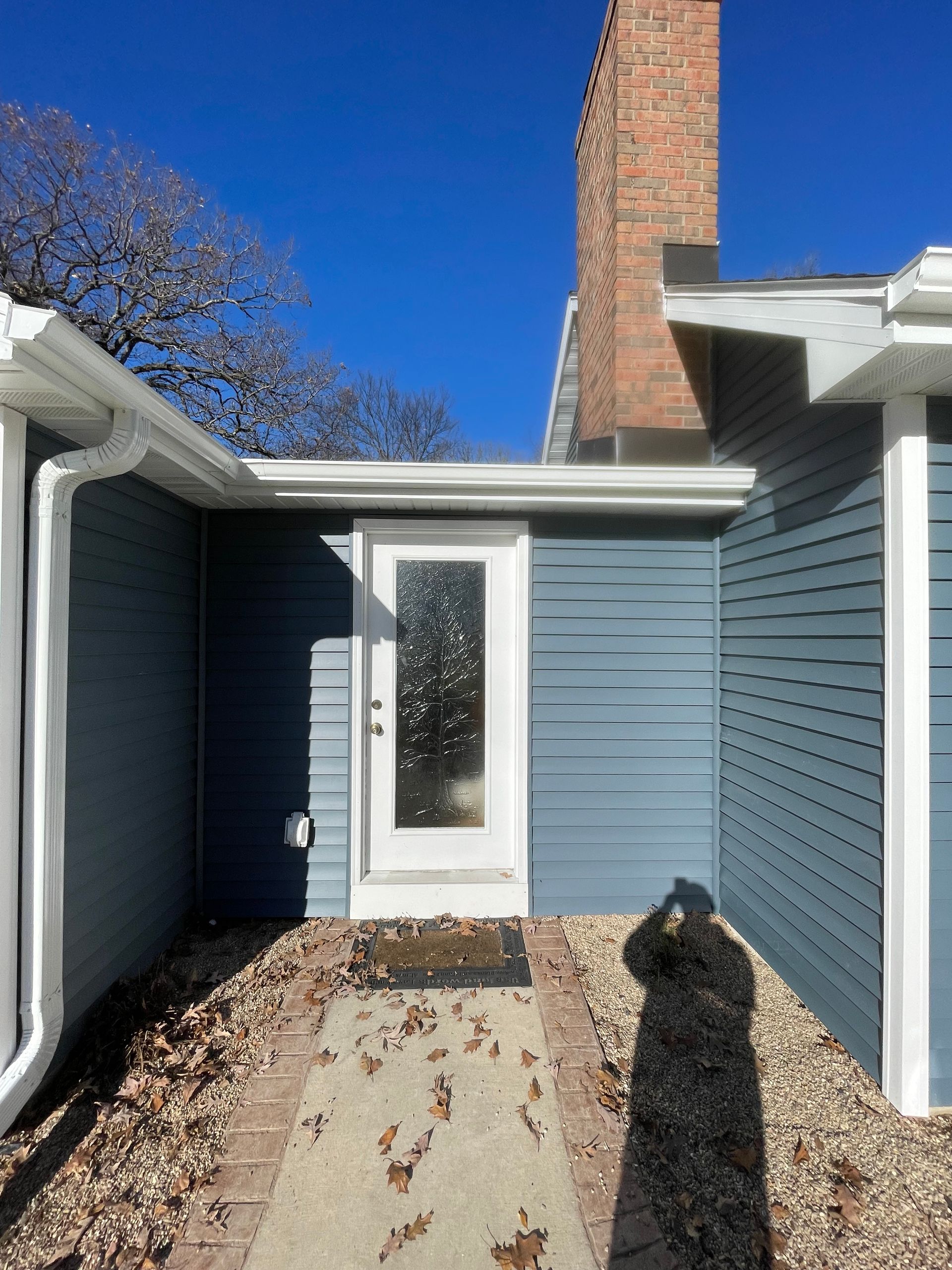 A blue house with a white door and a brick walkway