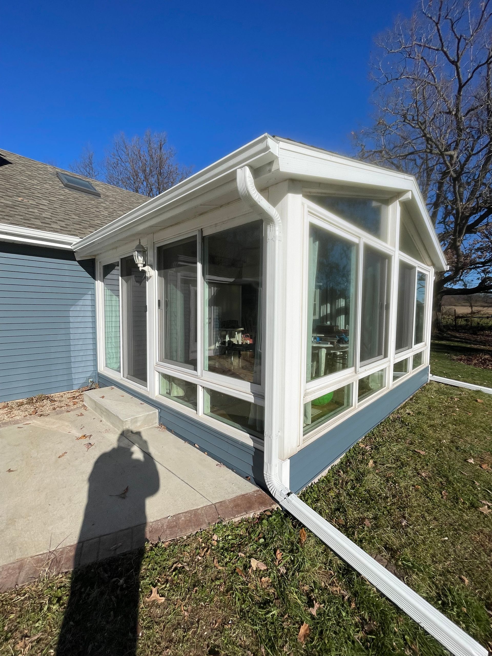 A sunroom with a lot of windows is sitting next to a house.