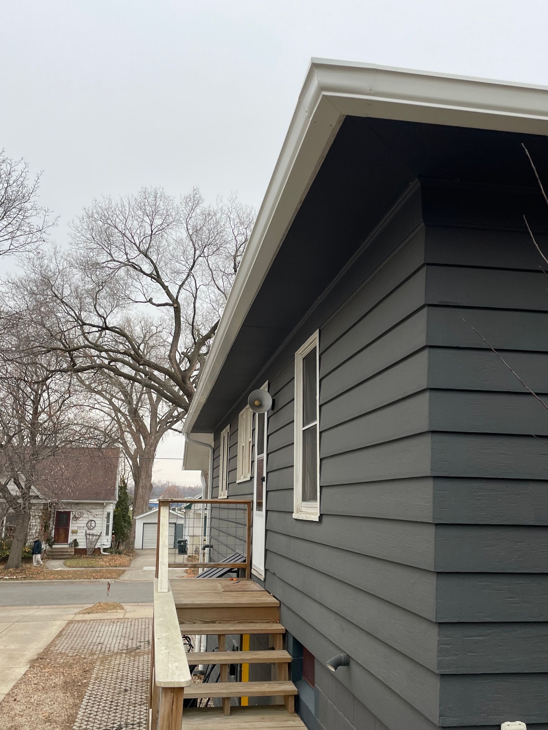 A gray house with a wooden deck and stairs