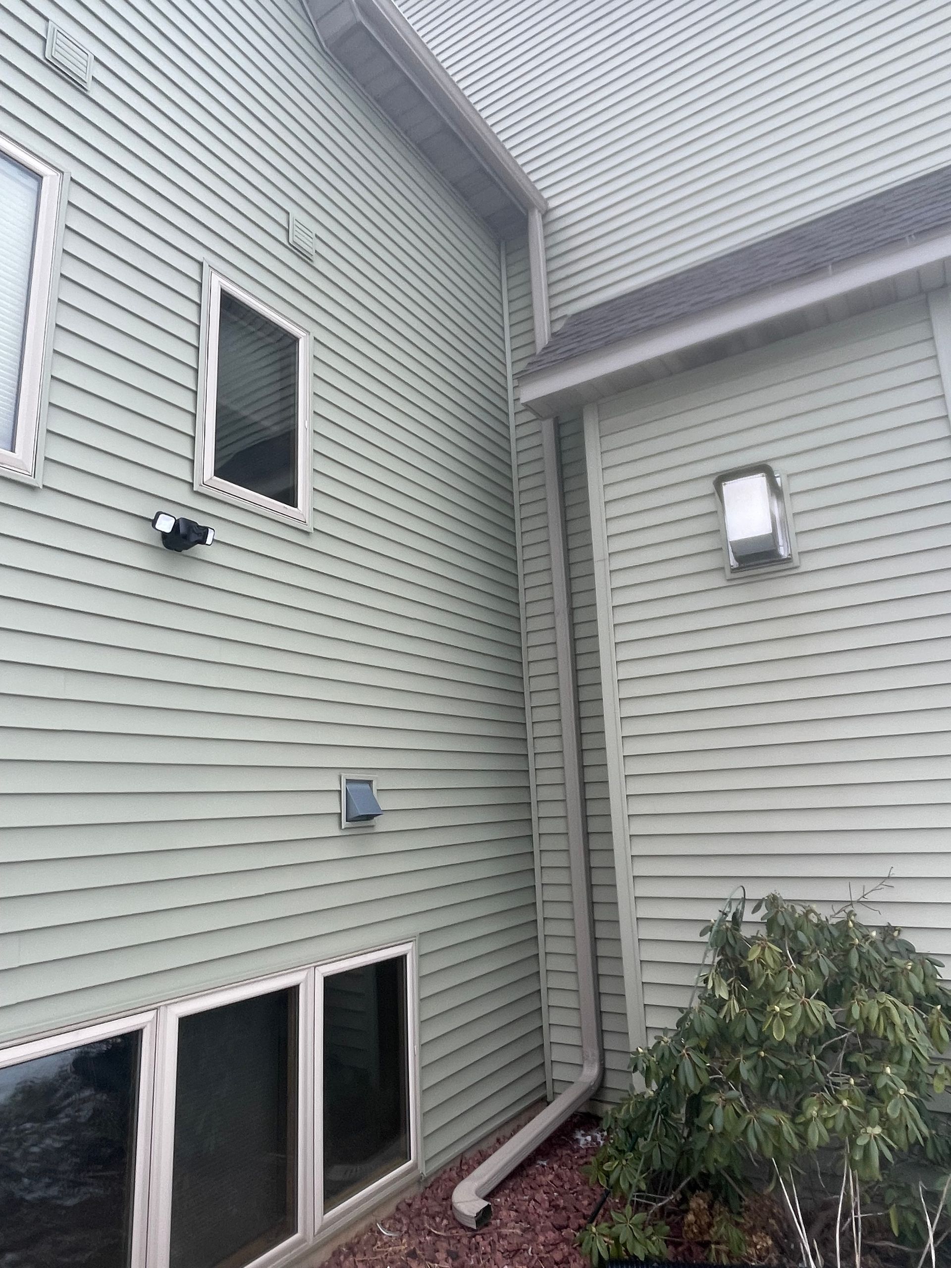 The side of a house with a drain pipe coming out of it.