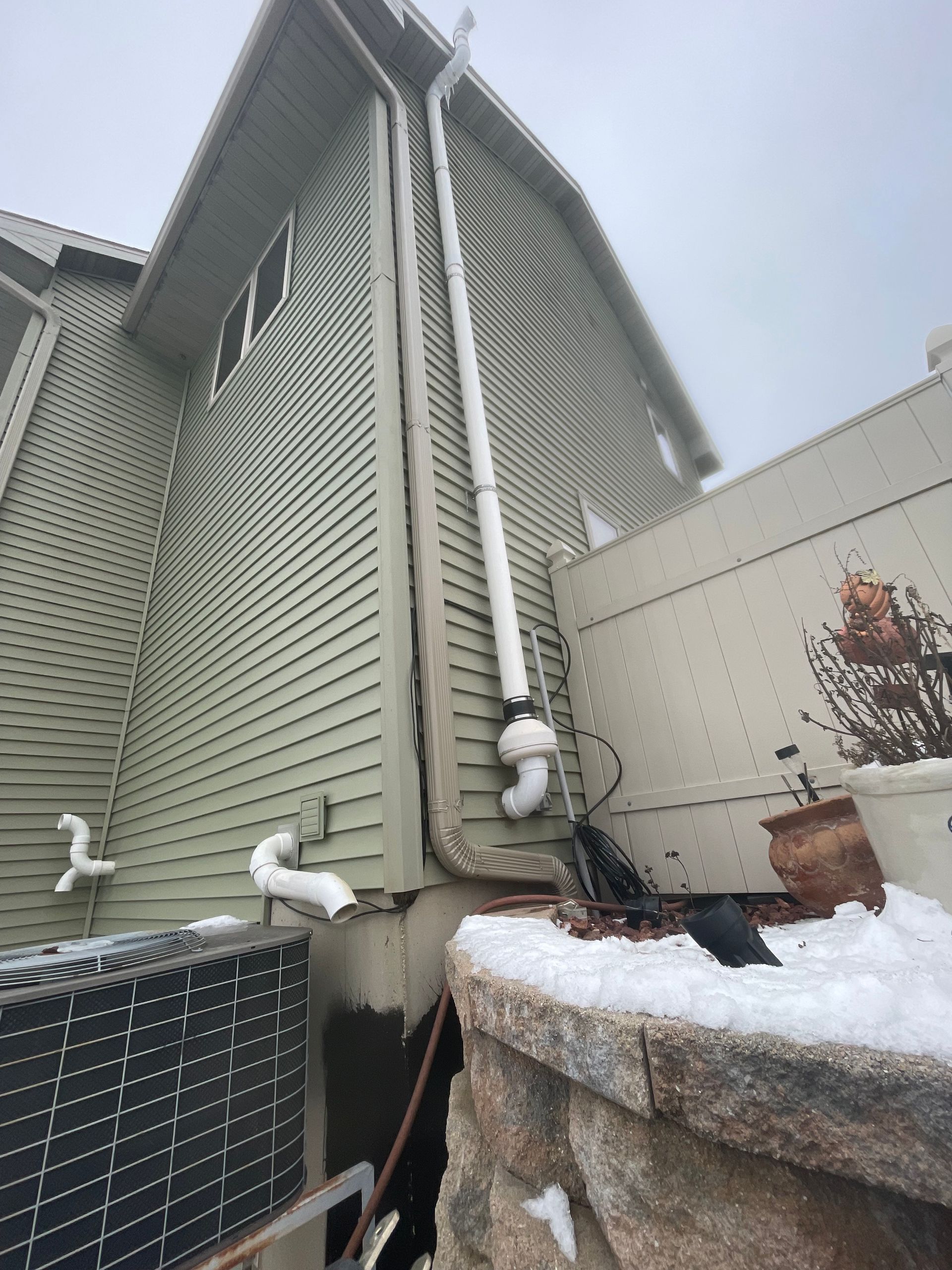 The side of a house with a white pipe coming out of it.