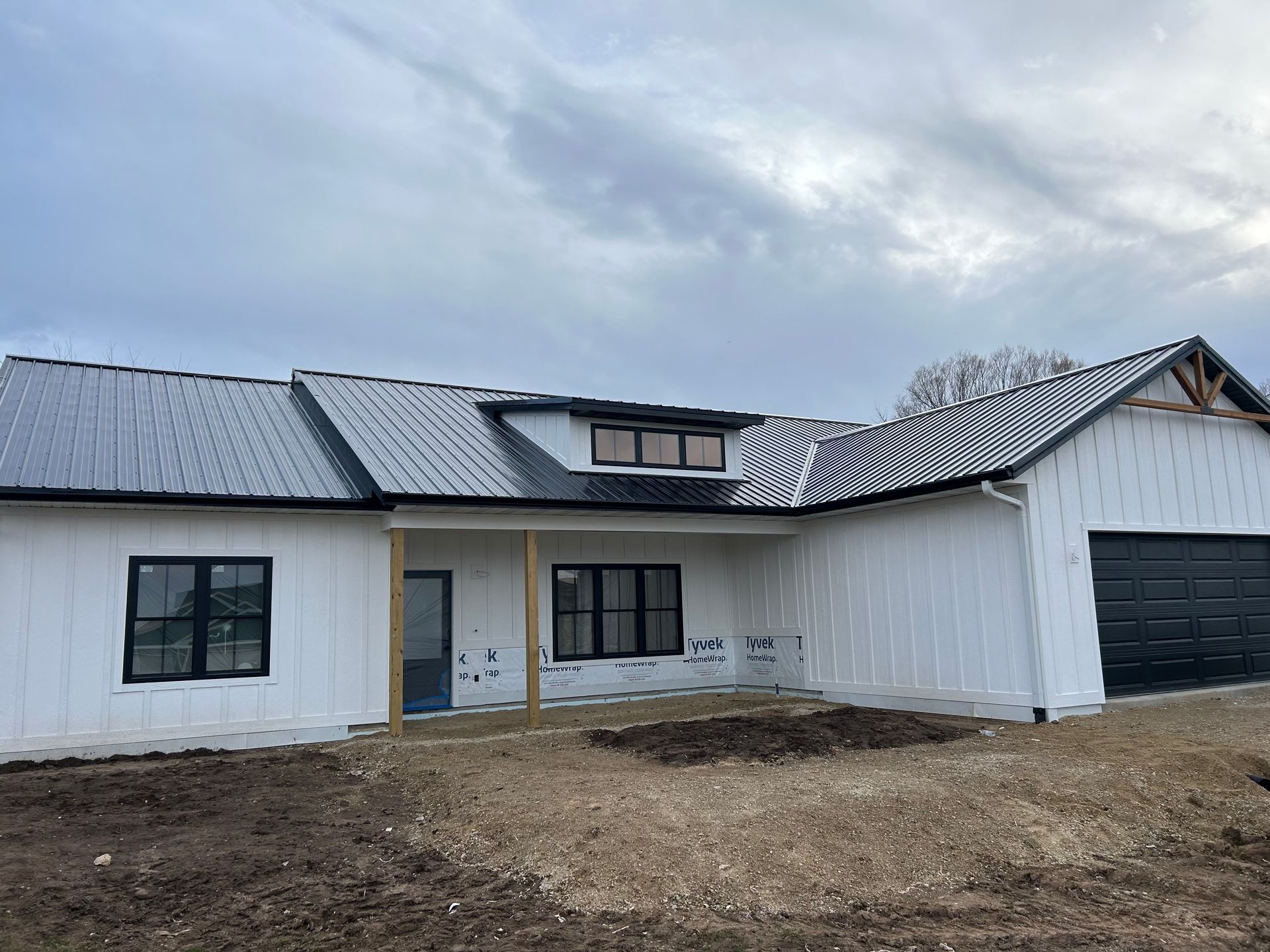 A white house with a black roof is being built.