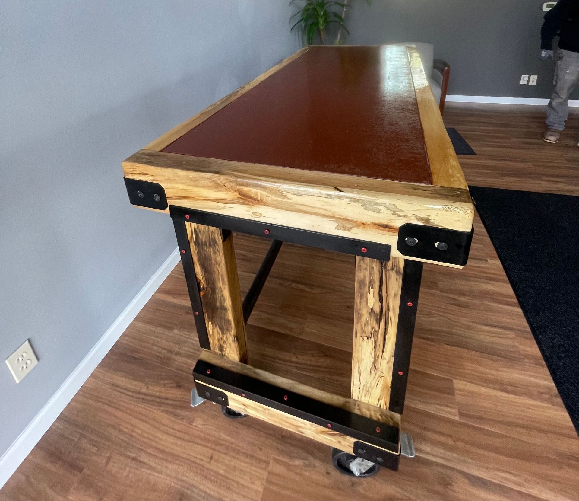 A wooden table with wheels is sitting on a wooden floor in a room.