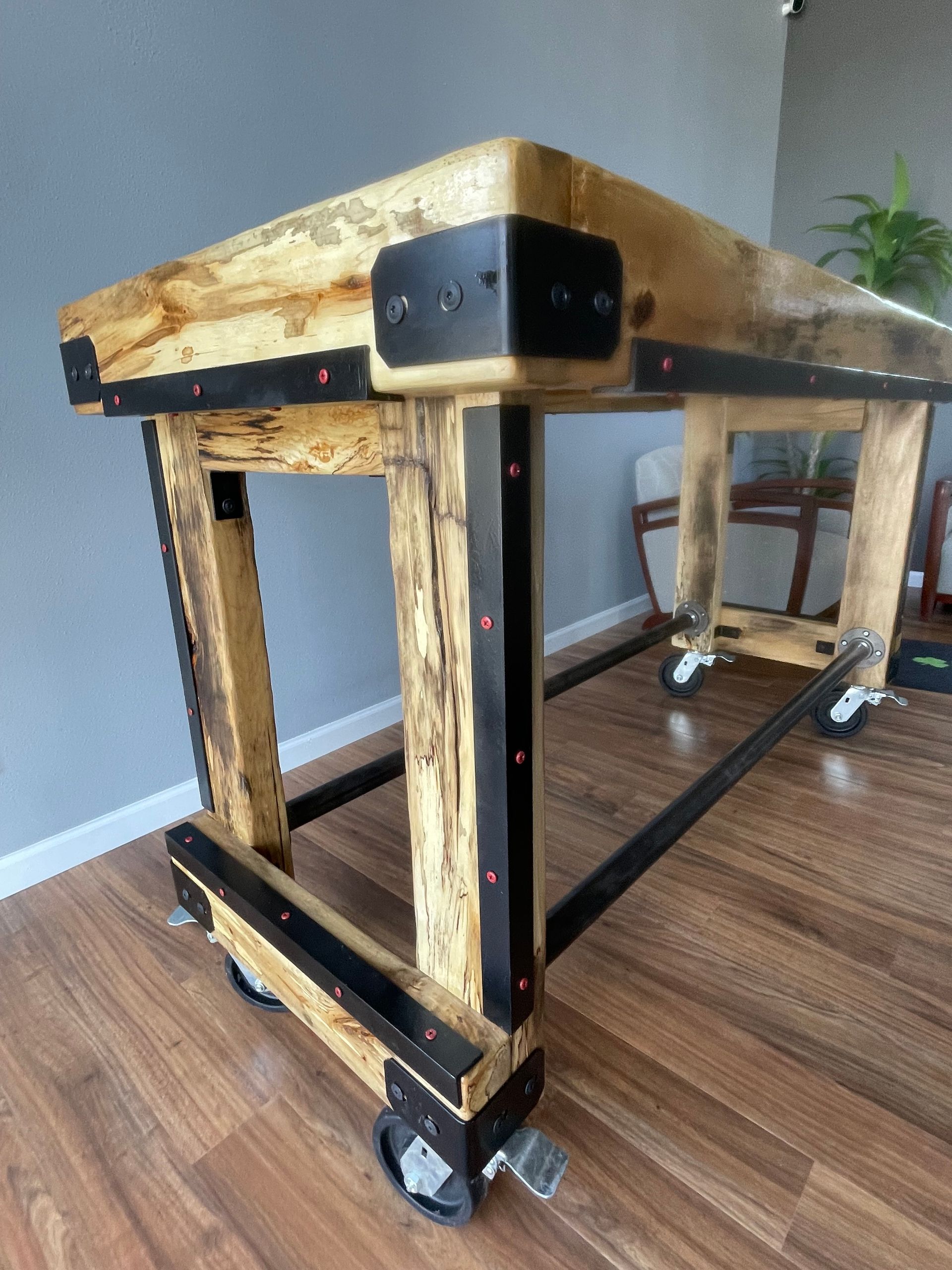 A wooden table with wheels is sitting on a wooden floor.
