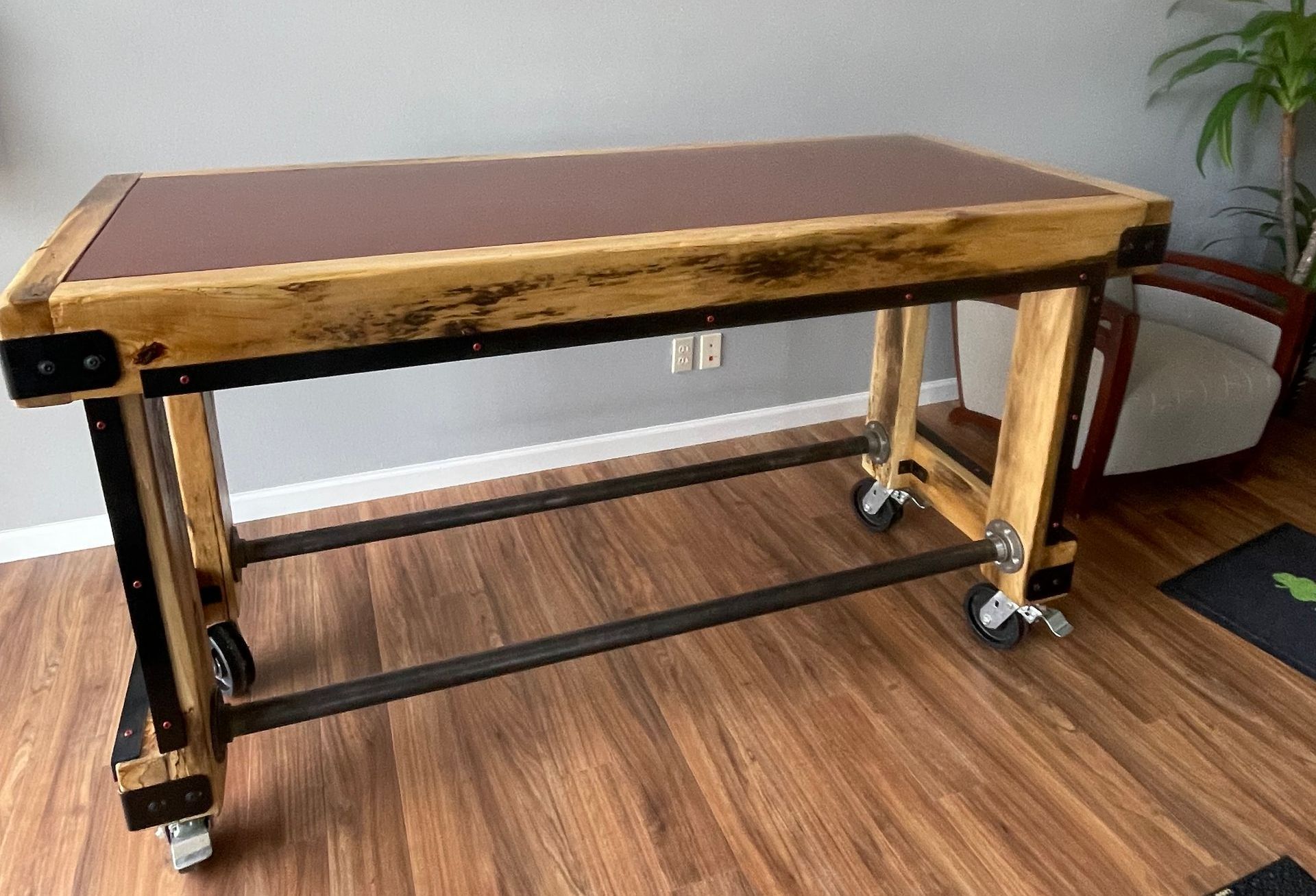A wooden table with wheels is sitting on a wooden floor.