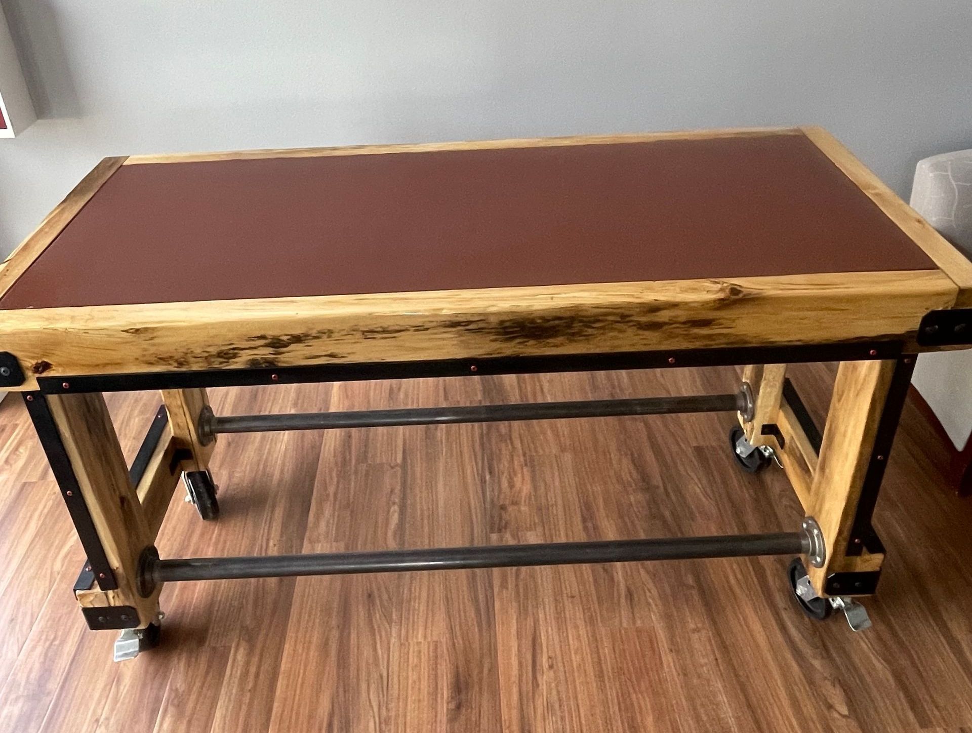 A wooden table with wheels is sitting on a wooden floor.