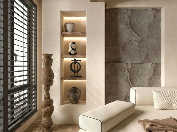 A minimalist living space with a window, built-in shelves, stone accent wall, and a light-toned sofa.