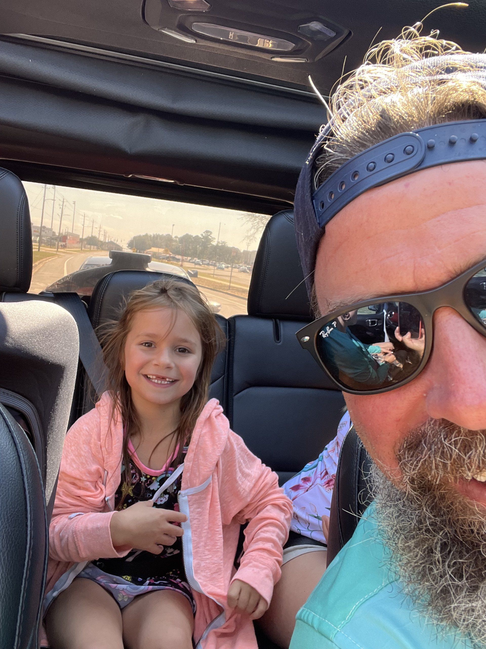 A dad and daughter taking a photo in Jeep