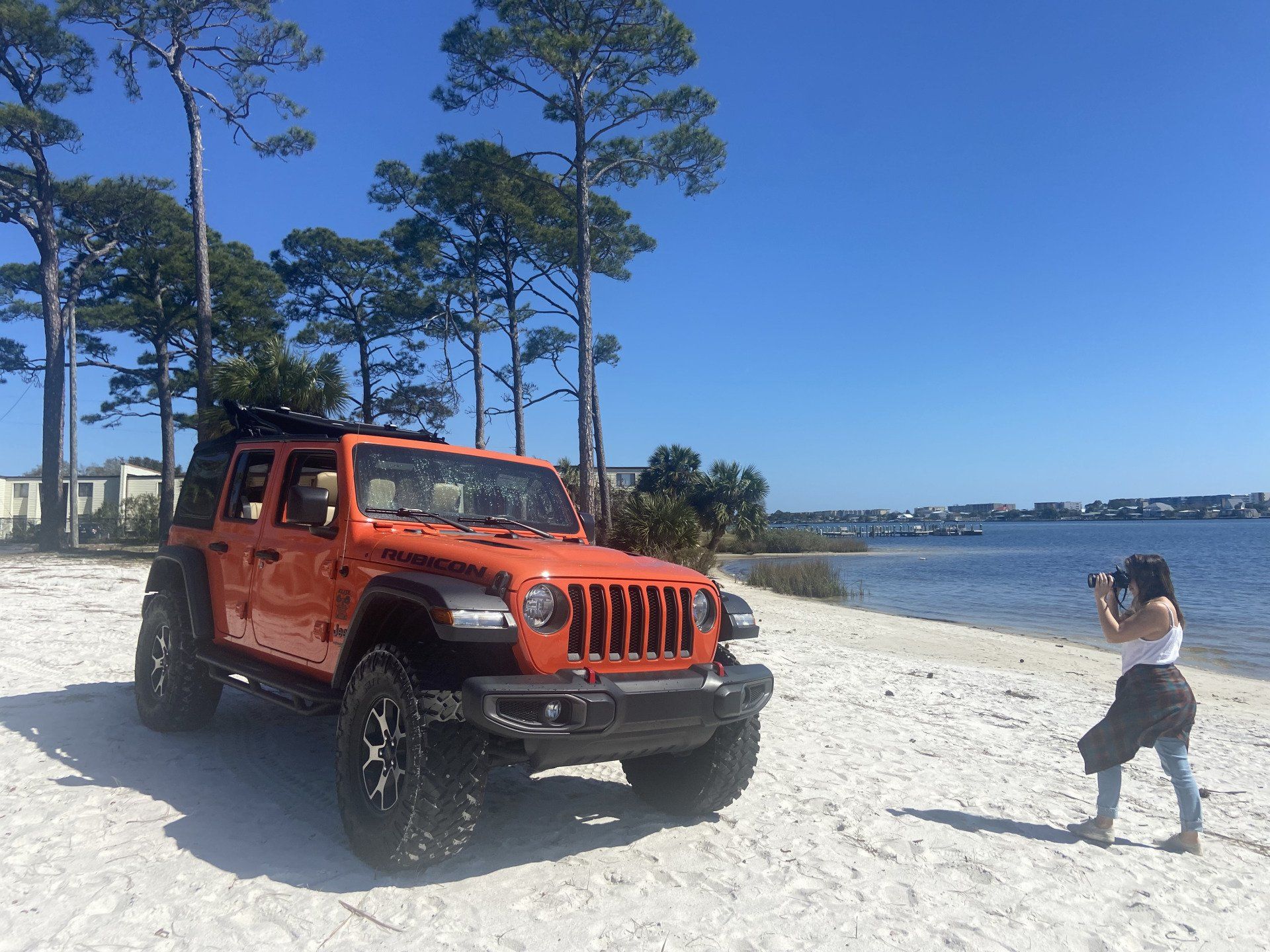woman taking photo of orange jeep