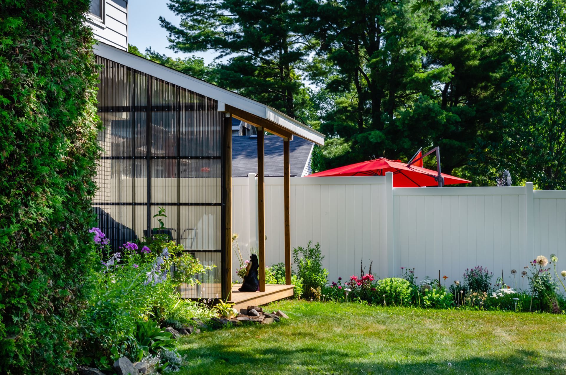 Sleek backyard sunroom addition with polycarbonate walls built onto a suburban home deck.