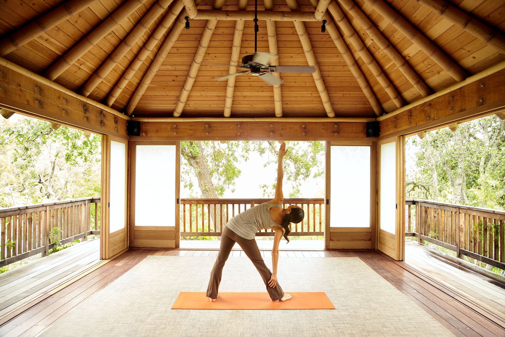 Person practicing yoga inside custom sunrooms with wooden ceiling and open outdoor view.