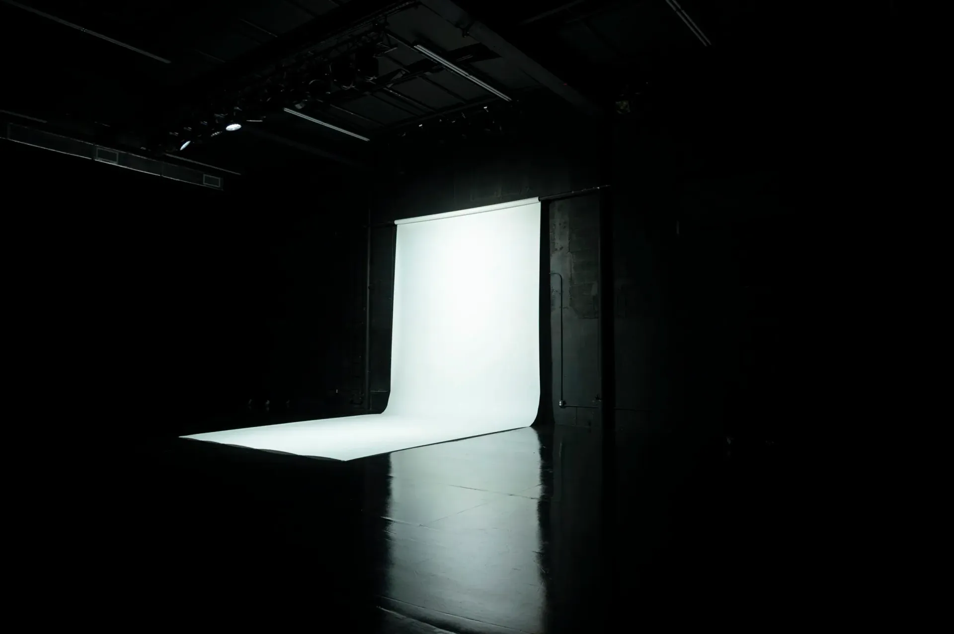 Dark room with a bright, rectangular light source on a wall and floor, casting a strong shadow.