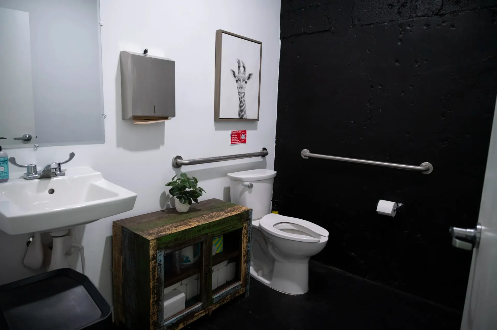 A restroom with a white sink, toilet, and a black wall.