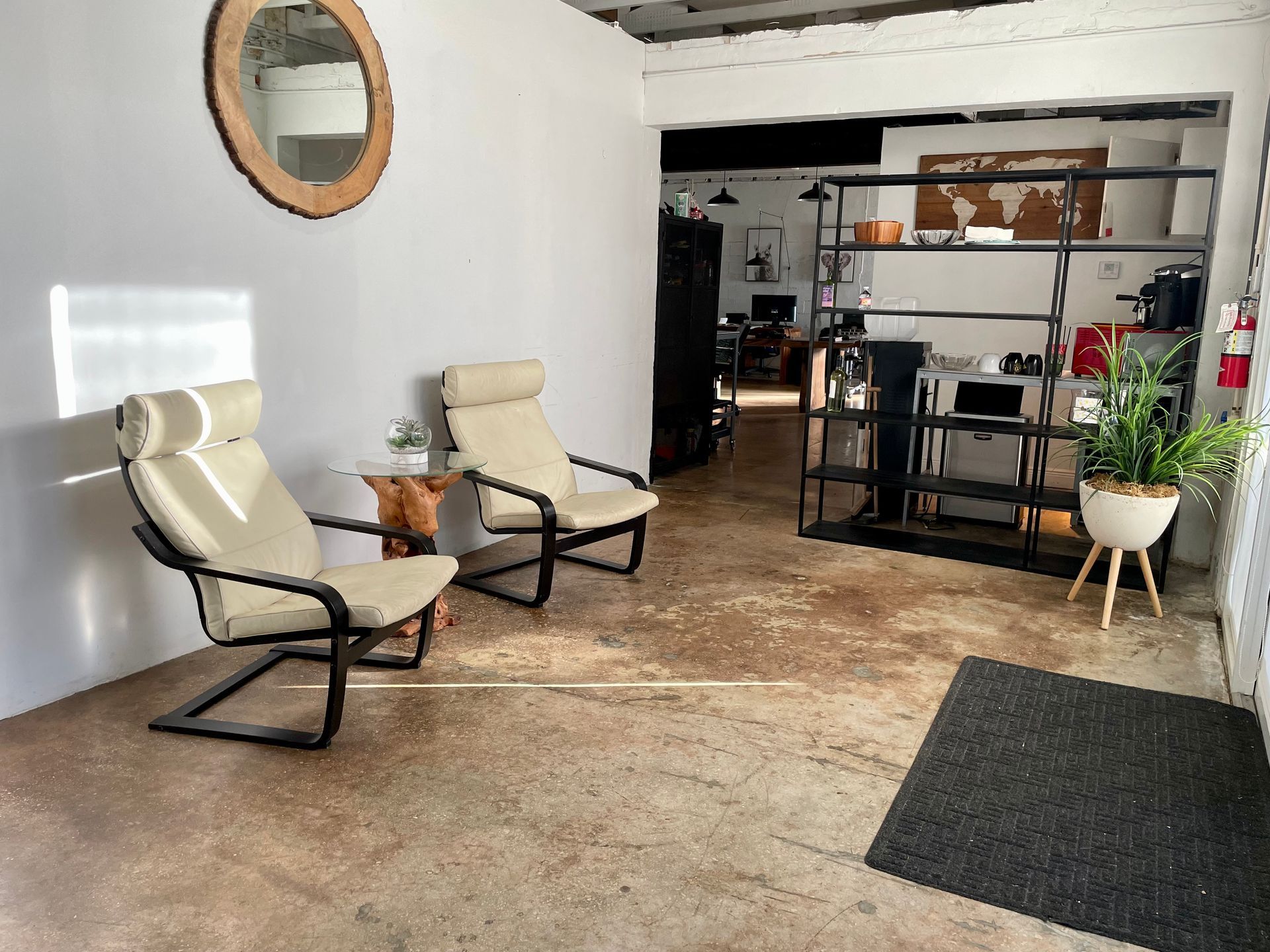 Two lounge chairs in a waiting area with a mirror, small table, and open shelving.