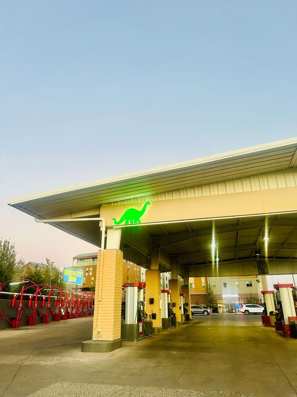 Gas station canopy with a green dinosaur logo.