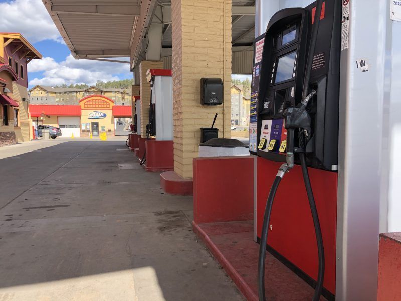 Gas pumps at a gas station with a building in the background. Red and beige color scheme.