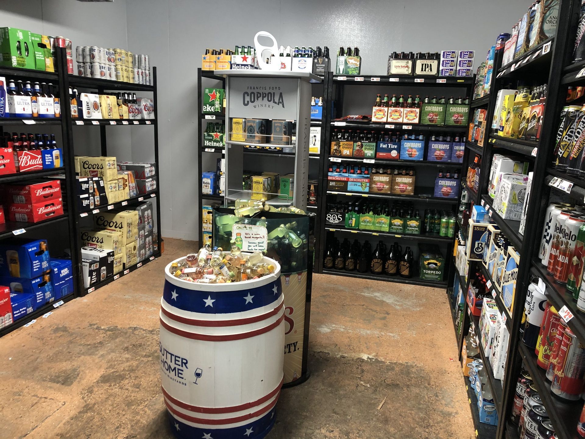 Interior of a beer and snack store with shelves full of products and a barrel display.